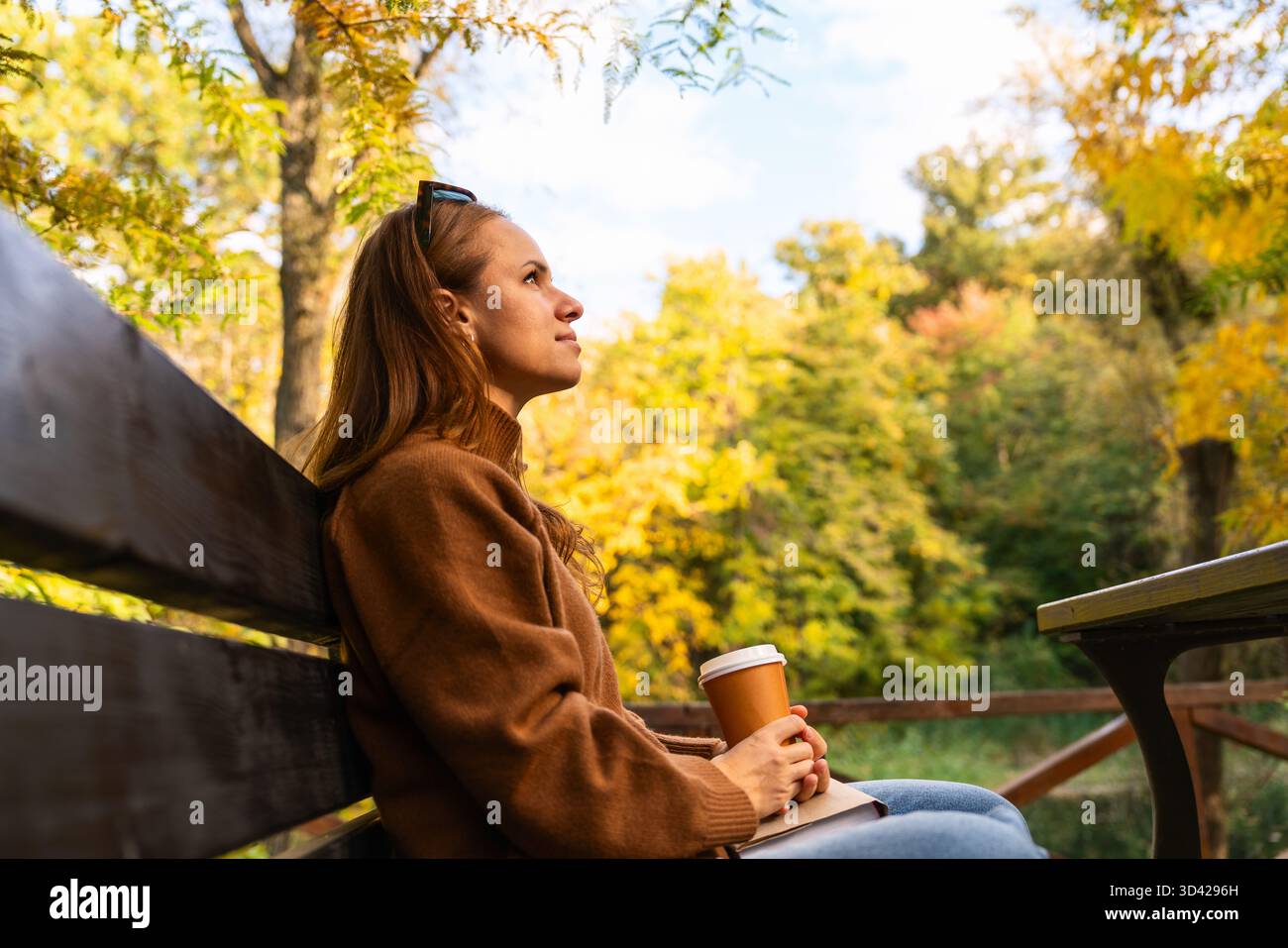 Frau mit heißem Getränk zum Mitnehmen im Stadtpark. Stockfoto