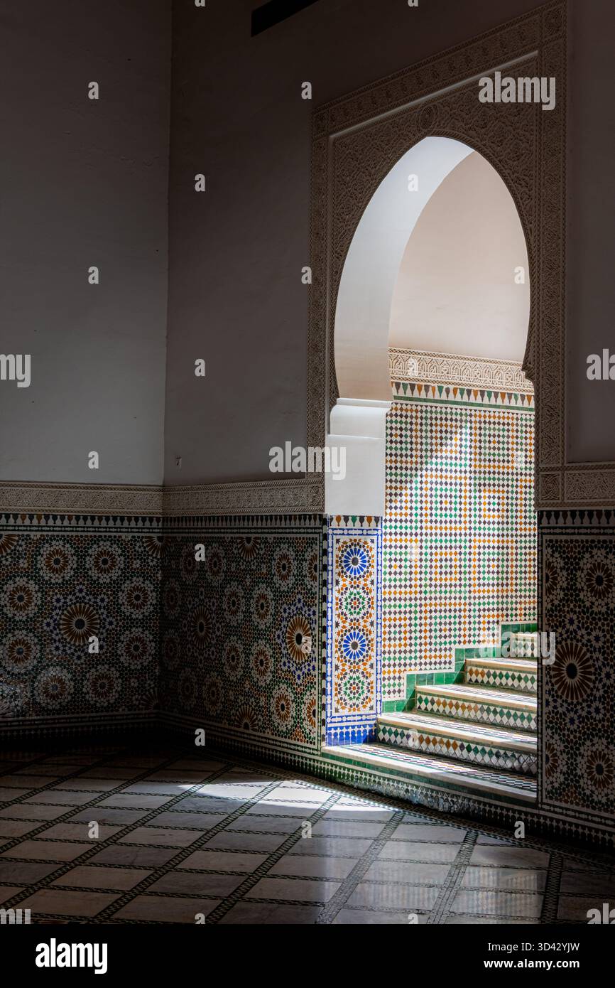 Harte Schatten fallen über eine bogenförmige Tür und Treppen und heben die geometrischen Linien und architektonischen Details hervor Stockfoto