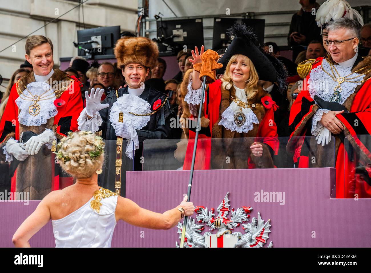 London, Großbritannien. November 2025. Eine Dame auf Stelzen aus der intitute of Couriers übergibt dem Bürgermeister die Handpuppe der Knowledge Eulen – die Lord Mayor’s Show 2025 stellt die 697. Lord Mayor of London, Dame Susan Langley DBE (im Bild), die zuvor aus der Aldgate-Gemeinde stammt, vor. Sie ist die dritte Frau, die das Amt seit über 800 Jahren innehatte, und die erste Frau, die den Titel „Lady Mayor of London“ erhielt. Die Show geht auf das frühe 13. Jahrhundert zurück, als König John gewährte, dass die City of London einen eigenen Bürgermeister ernennen könne, dass sie aber flussaufwärts nach Westminster kommen und der Krone Loyalität schwören müssten. Gutschrift: G Stockfoto