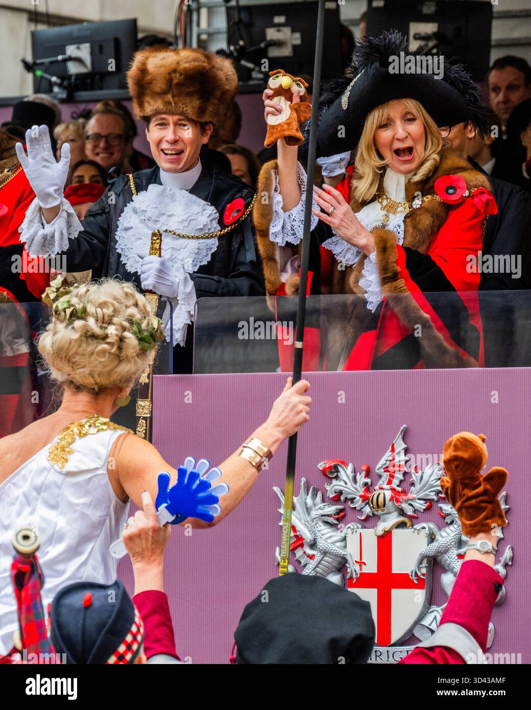 London, Großbritannien. November 2025. Eine Dame auf Stelzen aus der intitute of Couriers übergibt dem Bürgermeister die Handpuppe der Knowledge Eulen – die Lord Mayor’s Show 2025 stellt die 697. Lord Mayor of London, Dame Susan Langley DBE (im Bild), die zuvor aus der Aldgate-Gemeinde stammt, vor. Sie ist die dritte Frau, die das Amt seit über 800 Jahren innehatte, und die erste Frau, die den Titel „Lady Mayor of London“ erhielt. Die Show geht auf das frühe 13. Jahrhundert zurück, als König John gewährte, dass die City of London einen eigenen Bürgermeister ernennen könne, dass sie aber flussaufwärts nach Westminster kommen und der Krone Loyalität schwören müssten. Gutschrift: G Stockfoto