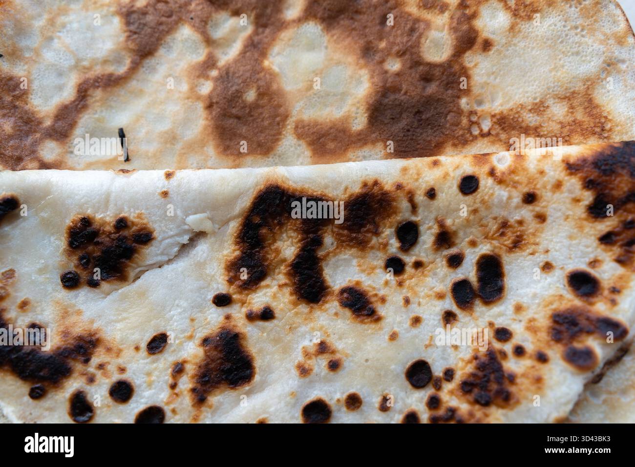 Detaillierte Makroaufnahme der unebenen Oberfläche eines Pfannkuchens mit goldbraunen und leicht gebrannten Mustern. Symbolisiert Komfortgerichte, Hausmannskost und Stockfoto