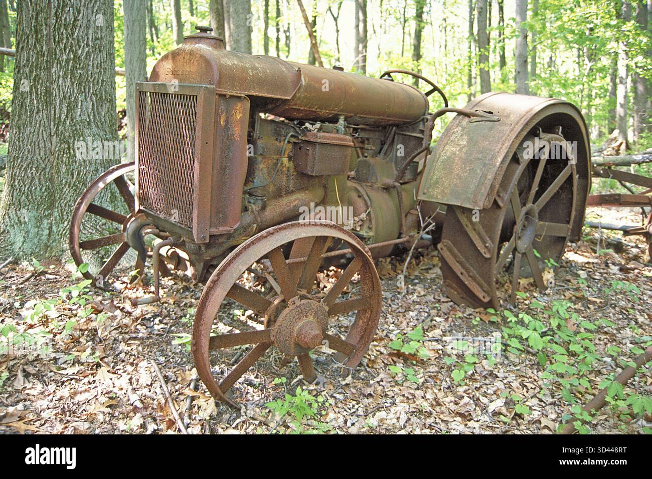 Rostiger amerikanischer Fordson-Traktor mit eisernen Reifen um 1900, abgesetzt in einem Waldgebiet, Marksboro, New Jersey, USA Stockfoto