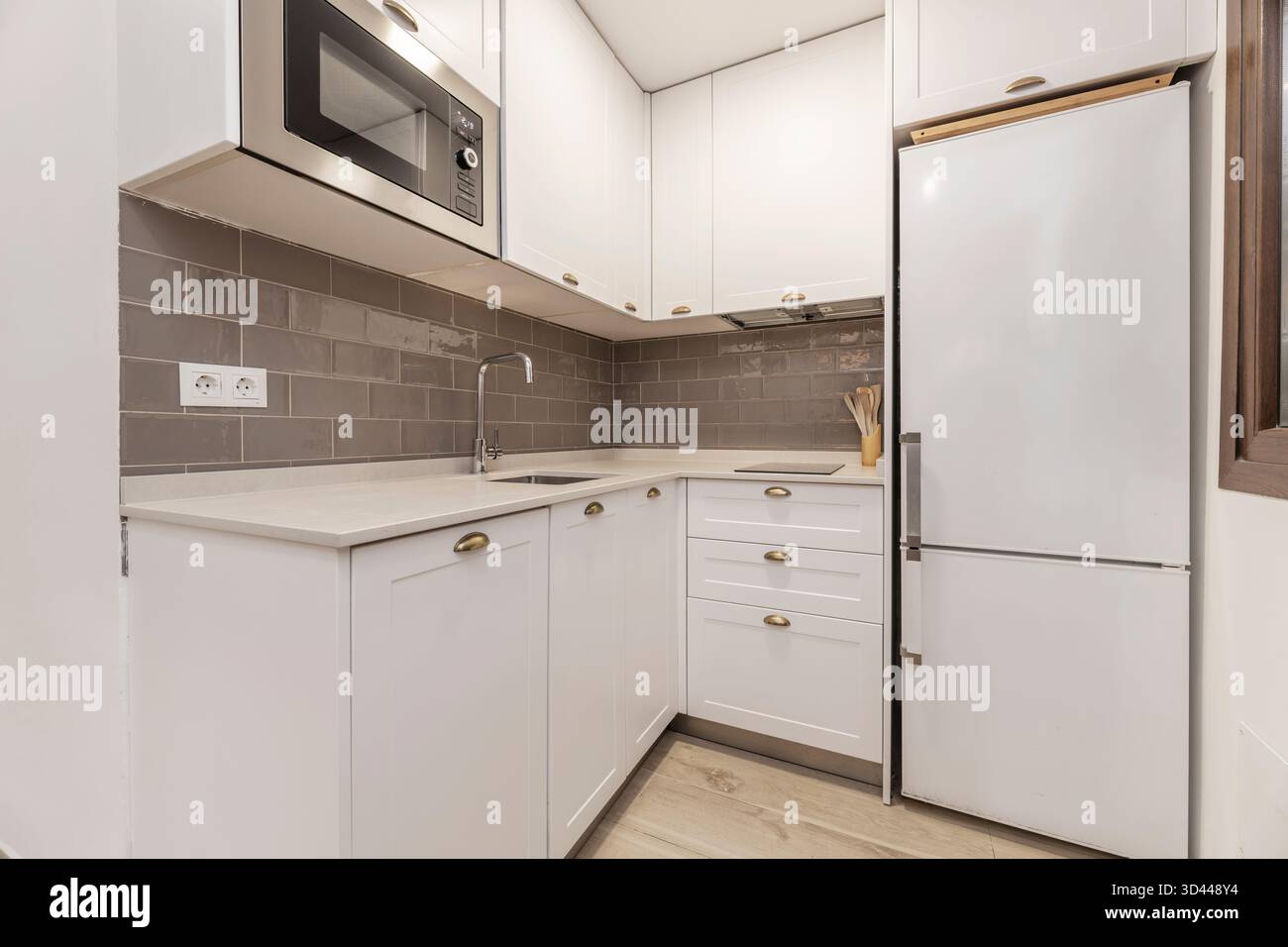 Foto einer Miniküche mit raumhohen Aufbewahrungslösungen, einschließlich offener Regale für häufig verwendete Gegenstände und geschlossener Schränke. Stockfoto