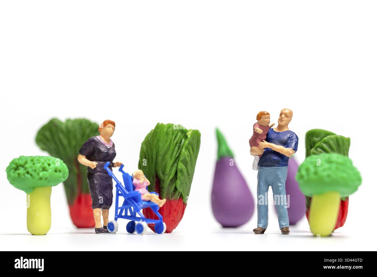 Miniaturmenschen, glückliche Familie, die auf einer Gemüsefarm ausruht. Konzept des Weltvegetarischen Tages Stockfoto