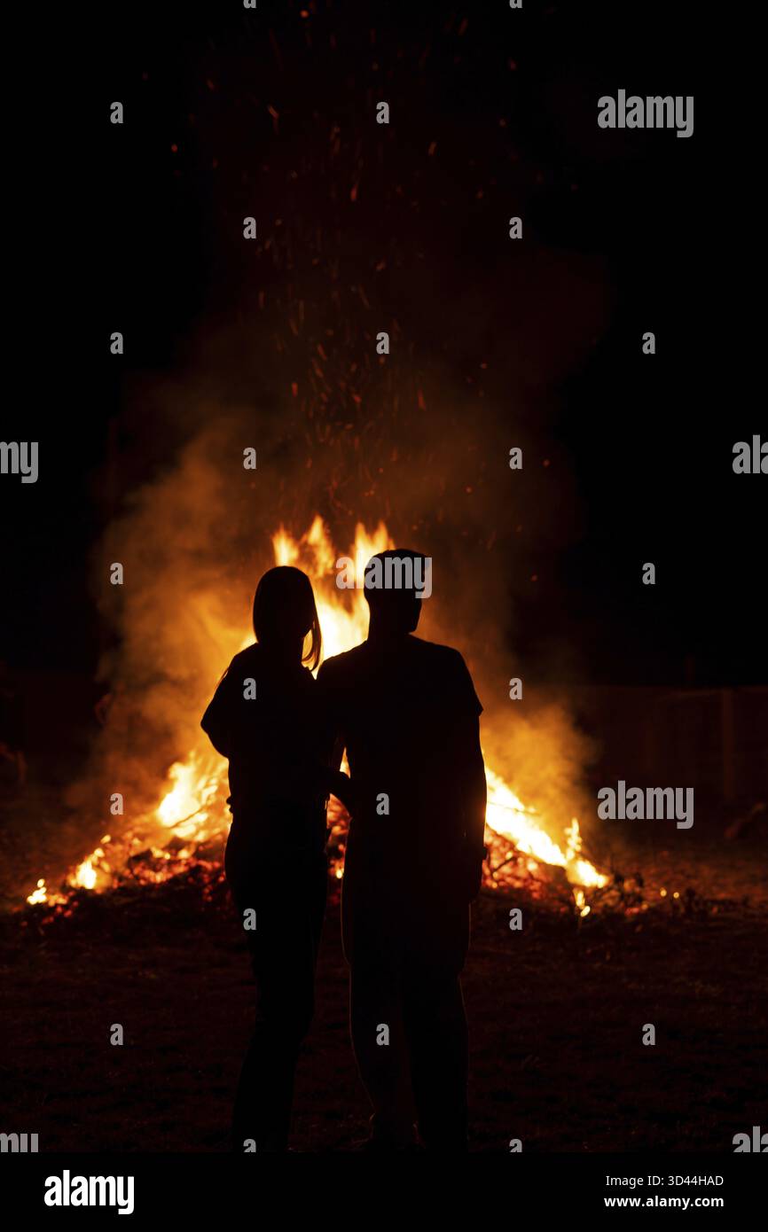 Silhouette eines Paares vor einem riesigen Lagerfeuer, typisch spanisches Fest der Sommersonnenwende, das die Nacht von San Juan oder St. John nennt Stockfoto