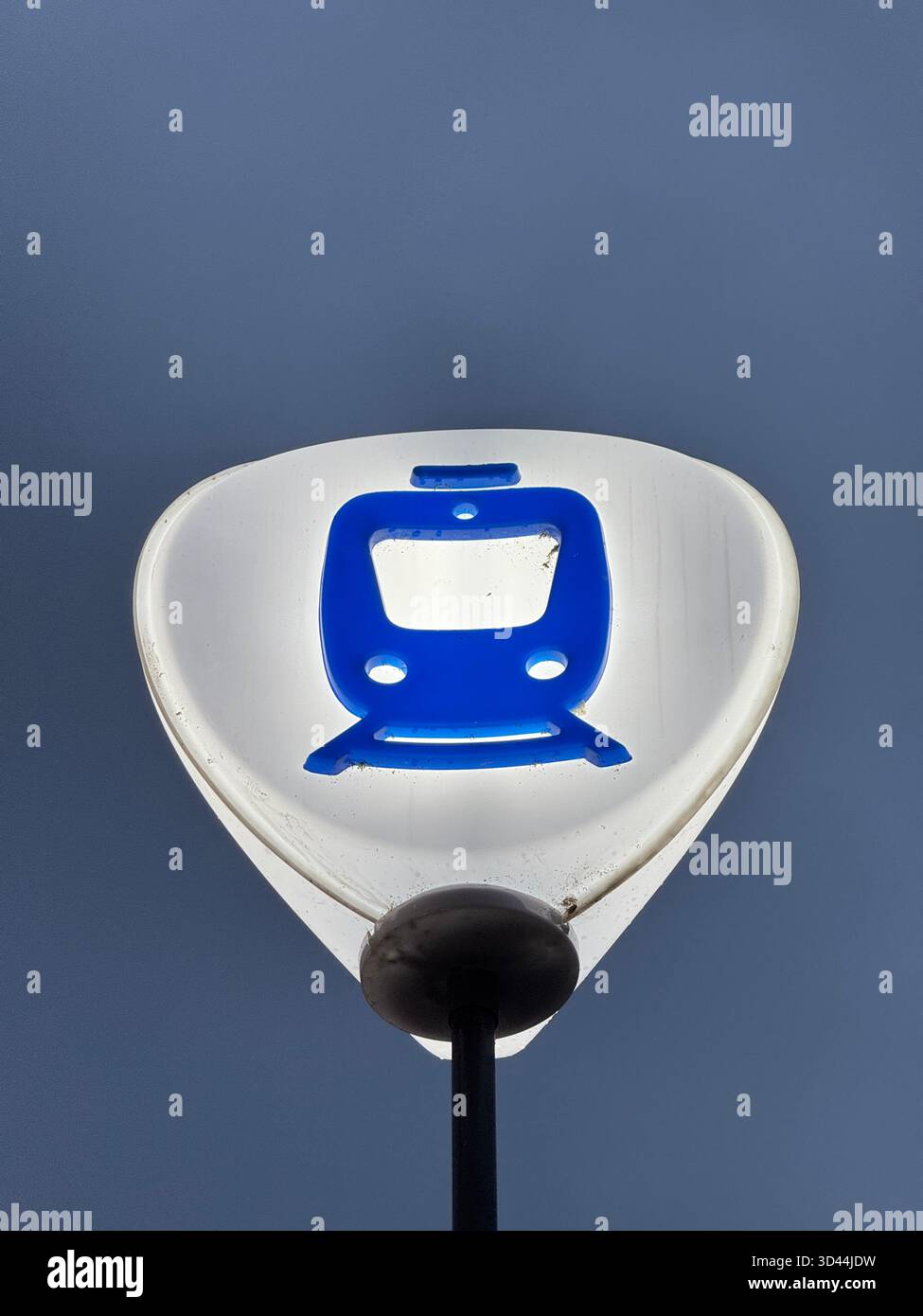 Ein blau-weißes Stoppschild für Pendlerzüge, fotografiert von unten vor einem klaren blauen Himmel. Symbol für öffentliche Verkehrsmittel in Schweden. - Smartphone-aufgenommenes Stockfoto