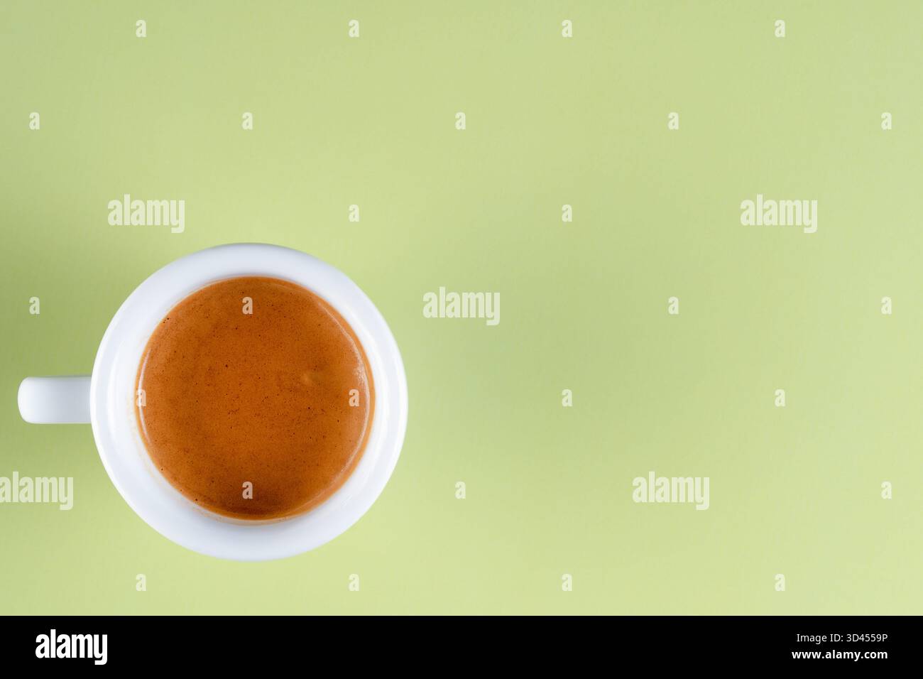 Blick von oben auf doppelten Espresso in weißer Tasse auf grünem Hintergrund Stockfoto