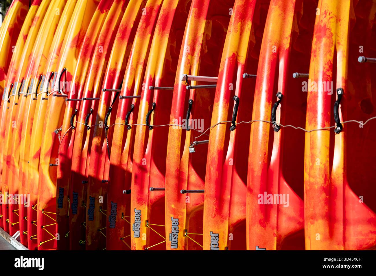 Farbenfrohe orangene Paddelbretter und Surfbretter oder Surfbretter, die in einem Rack zum Verleih oder Verkauf in der Harborwalk Marina, Destin Florida, USA, angeordnet sind. Stockfoto