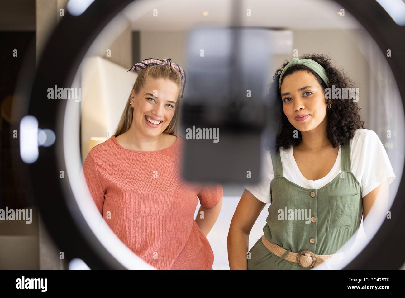 Aufnahmen verschiedener weiblicher Freunde, die im Heimstudio stehen, mit Ringlicht und Smartphone Stockfoto