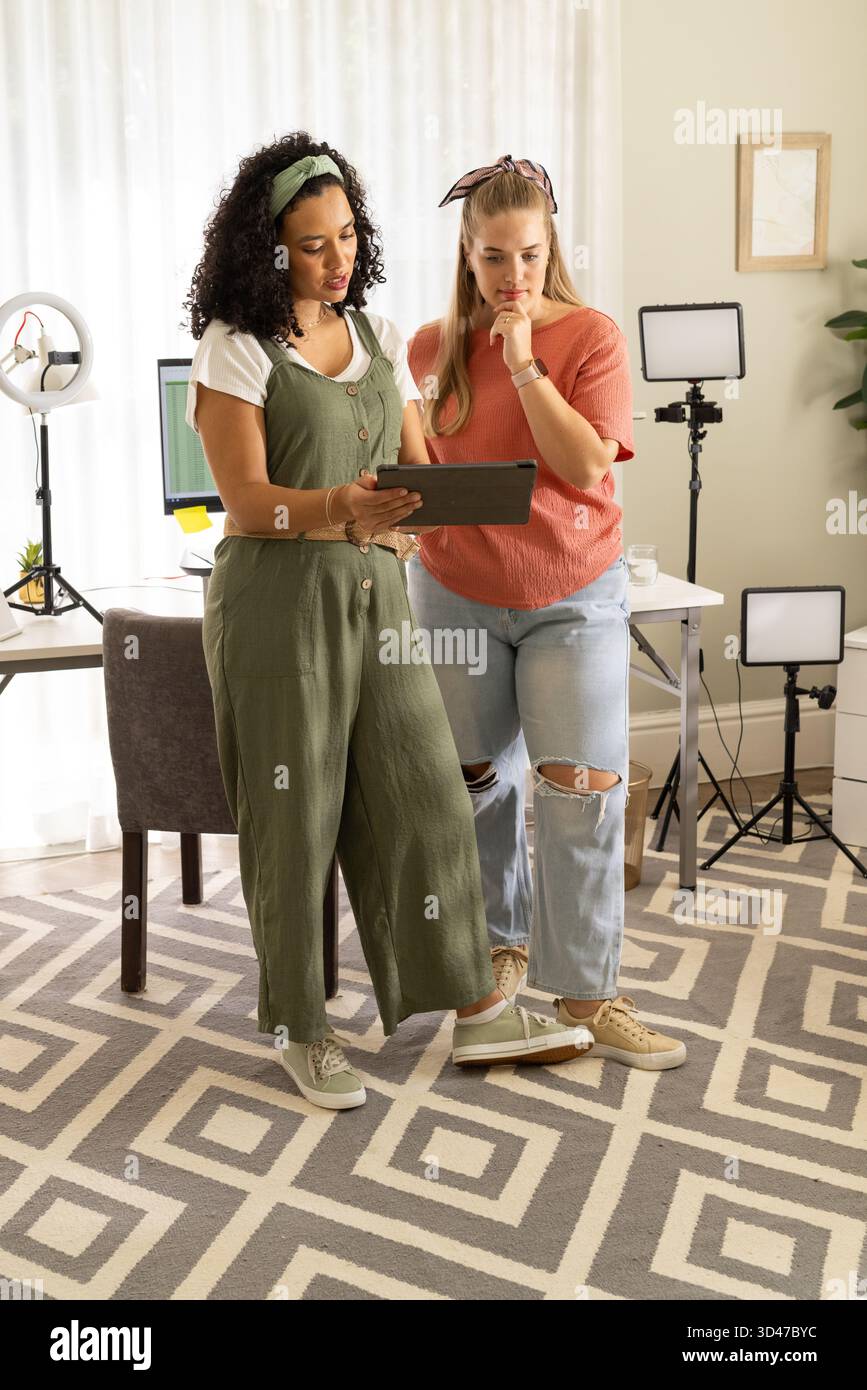 Verschiedene Kollegen, die ein Tablet im Home Office mit Ringlicht und Monitor bewerten Stockfoto