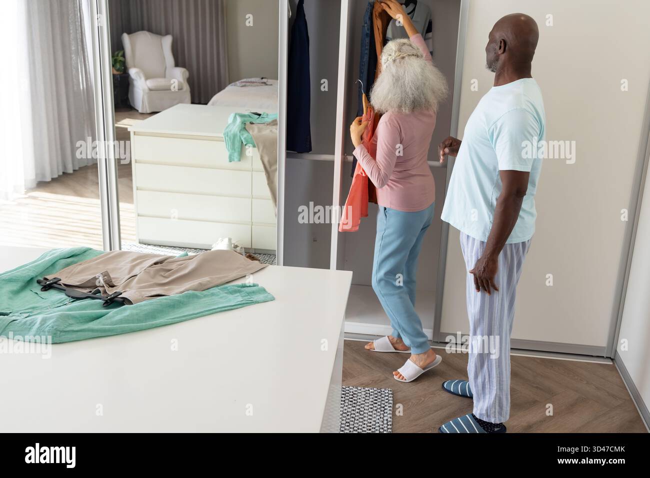 Das moderne Schlafzimmer mit schiebetürem Kleiderschrank und Spiegel bietet ein ausgesuchtes Seniorenpaar Stockfoto