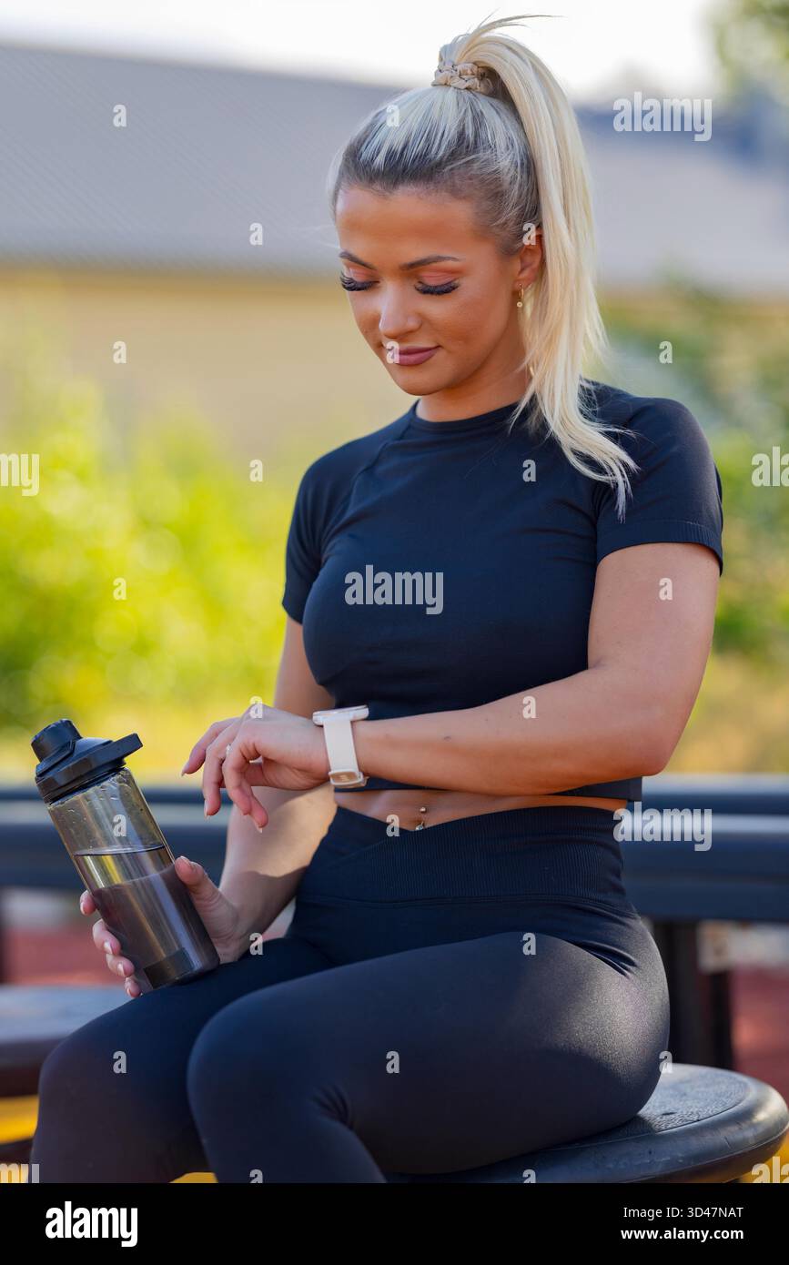 Frau in sportlicher Kleidung, die Smartwatch während des Workouts im Freien verwendet Stockfoto