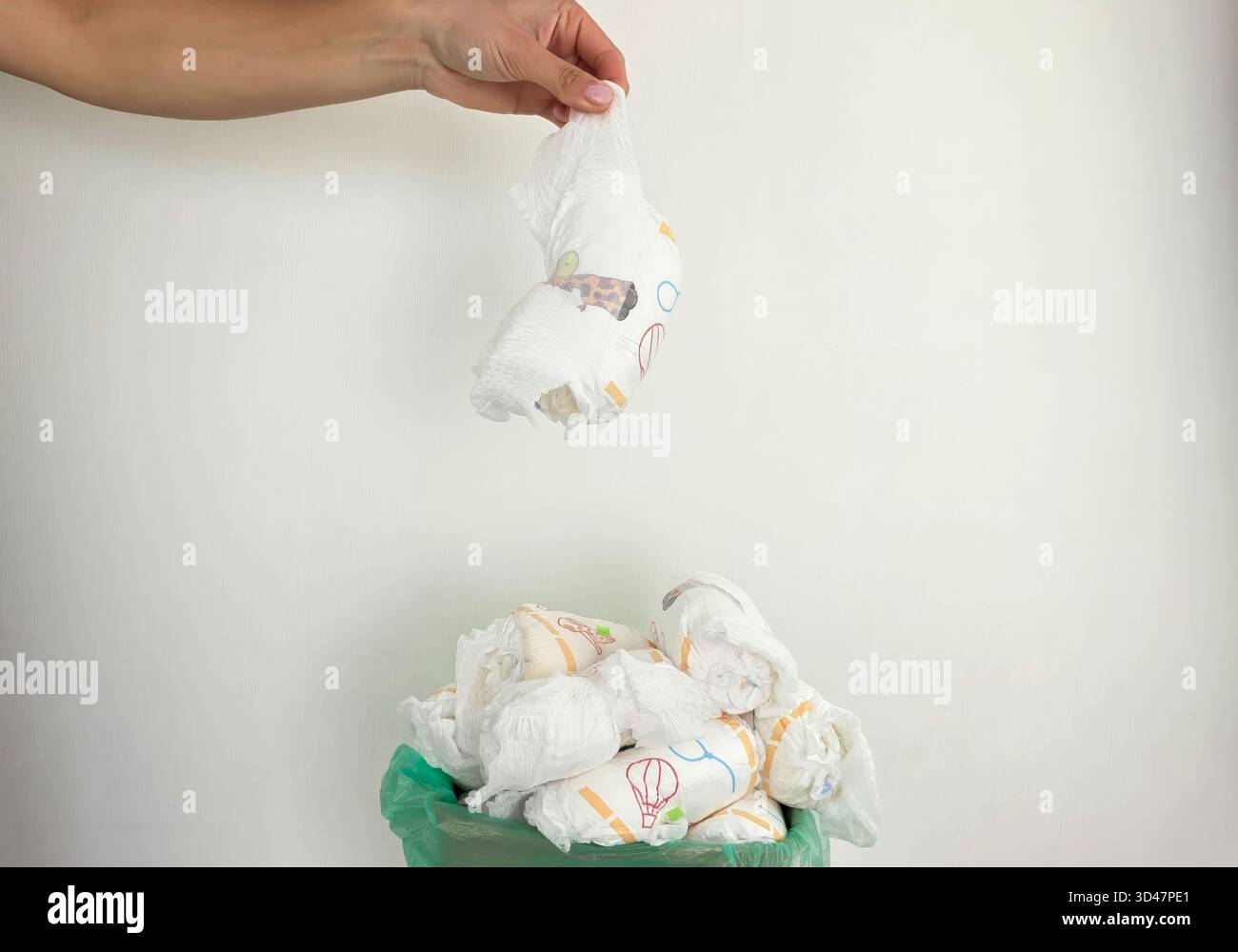 Die Hand wirft gebrauchte Windeln in den vollen Papierkorb. Stockfoto