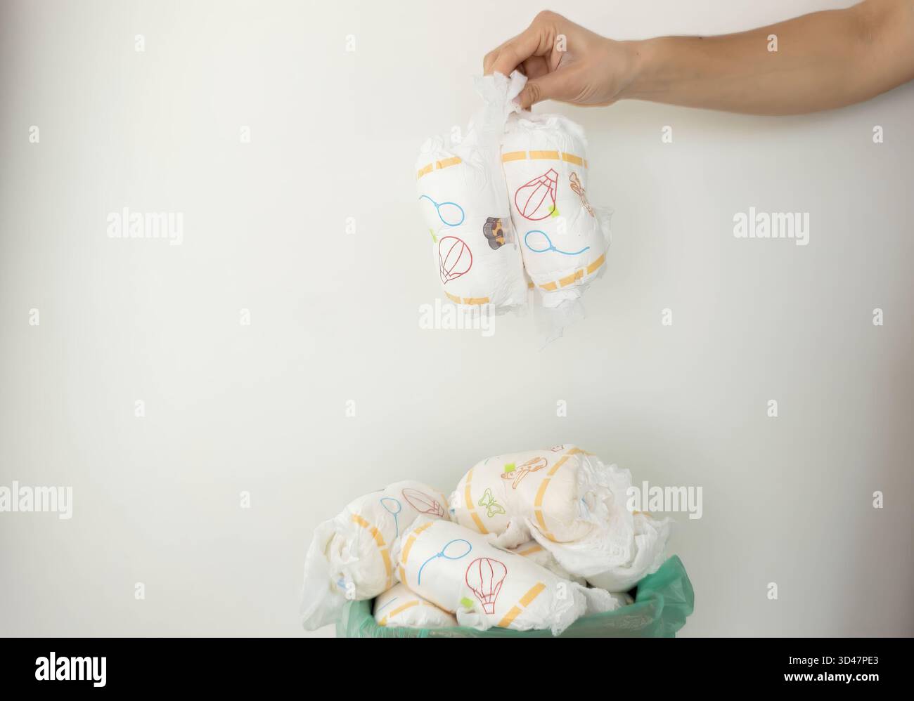 Die Hand wirft gebrauchte Windeln in den vollen Papierkorb. Stockfoto