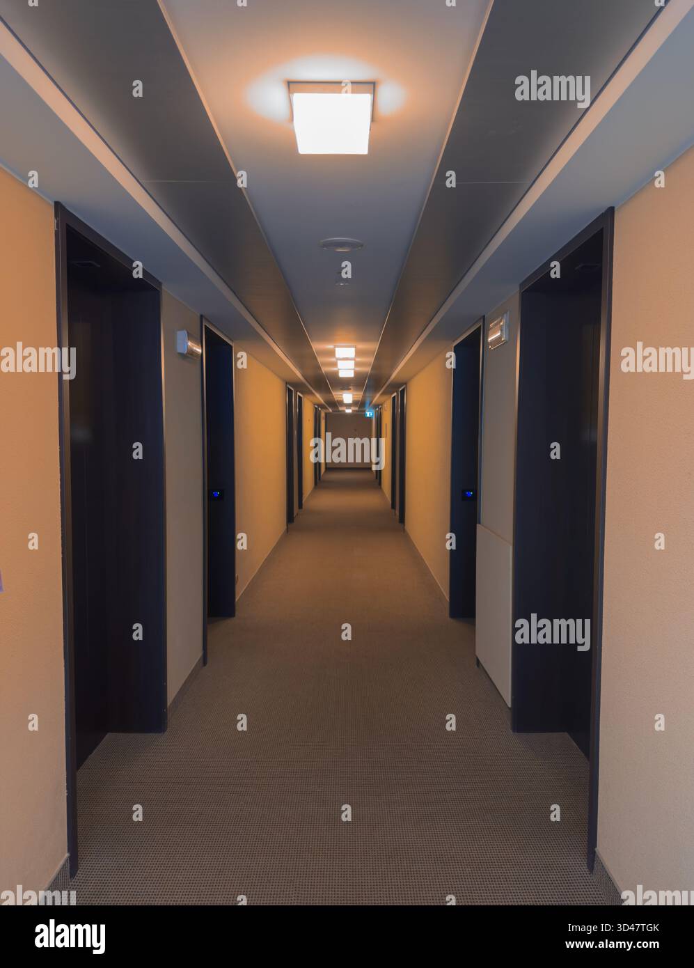 Moderner Hotelflur mit warmen Lichtern und offenen Zimmertüren Stockfoto