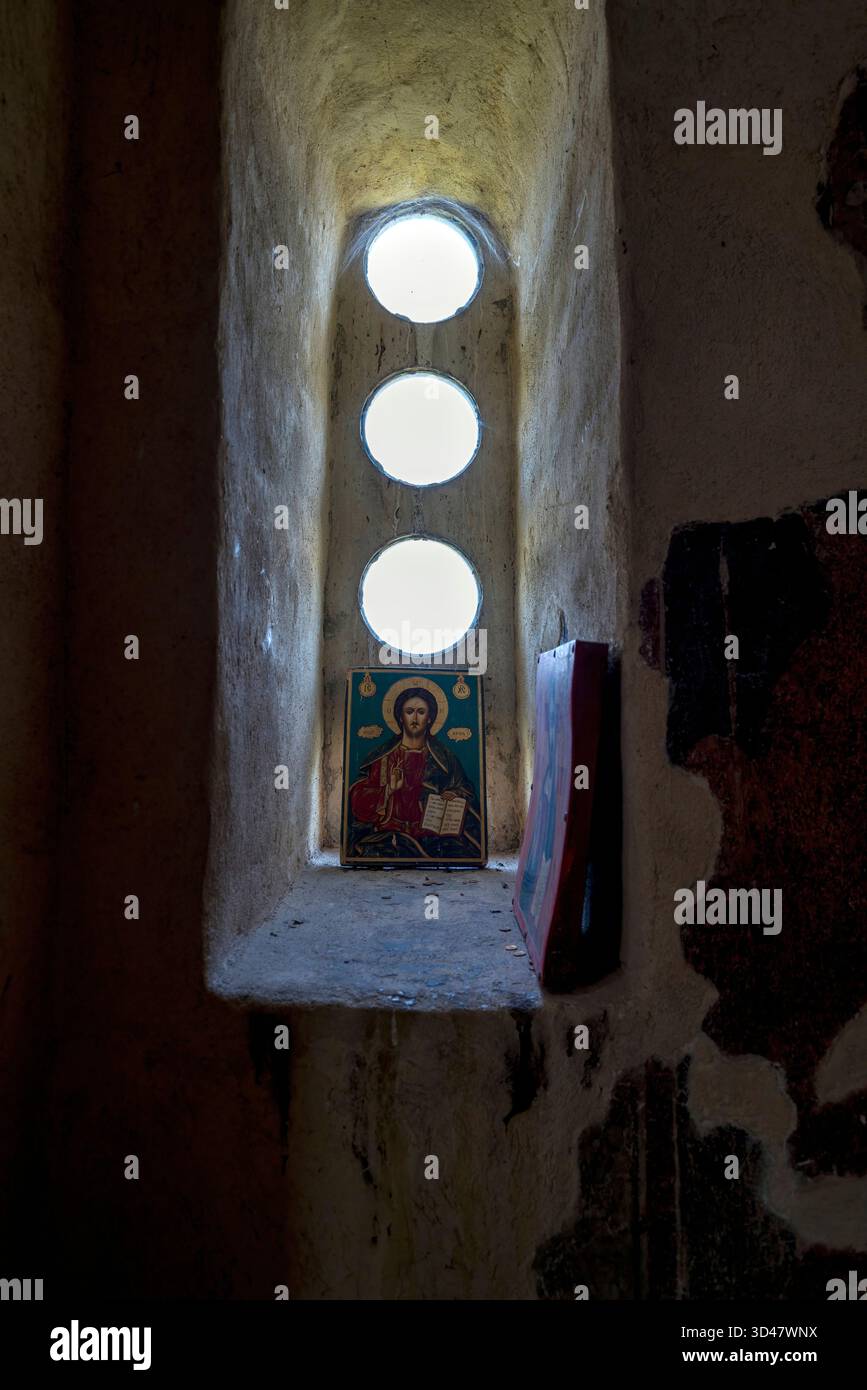 Eine religiöse Ikone Christi ruht auf einem Felsvorsprung unter drei runden Fenstern in den alten Mauern der Festung Asen, Bulgarien. Stockfoto