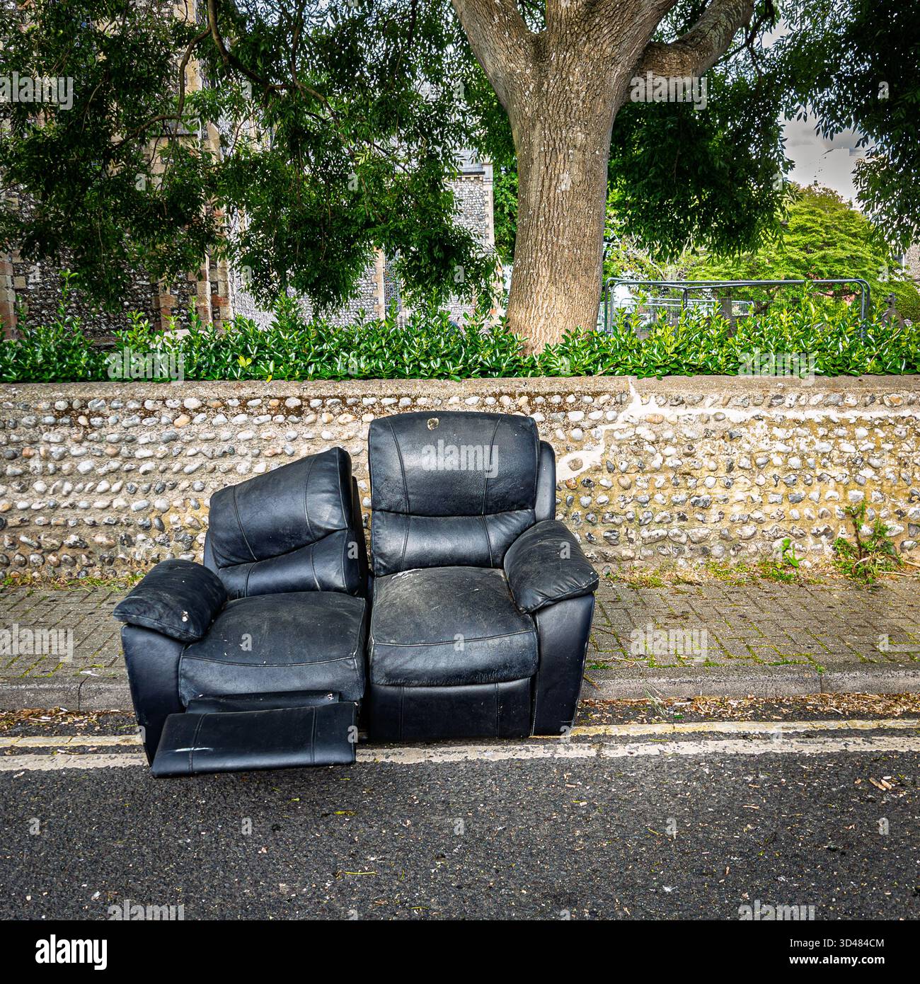 Ein verlassenes schwarzes Ledersofa in einer Straße im Stadtzentrum von Worthing - Smartphone-aufgenommenes Stockfoto