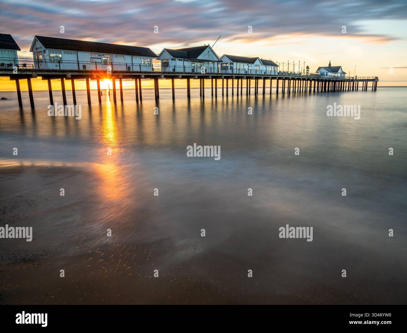 Lassen Sie Licht auf nassem Sand unter dem Southwold Pier an einem ruhigen Morgen erscheinen Stockfoto