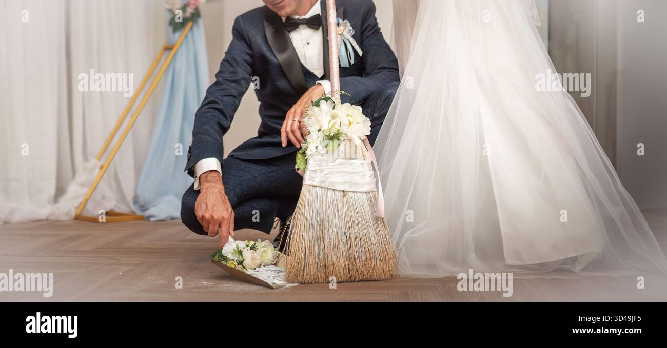 Die Braut und der Bräutigam fegen feierlich die Fliesen der zerbrochenen Platte. Traditionelles slowakisches Hochzeitsritual Stockfoto
