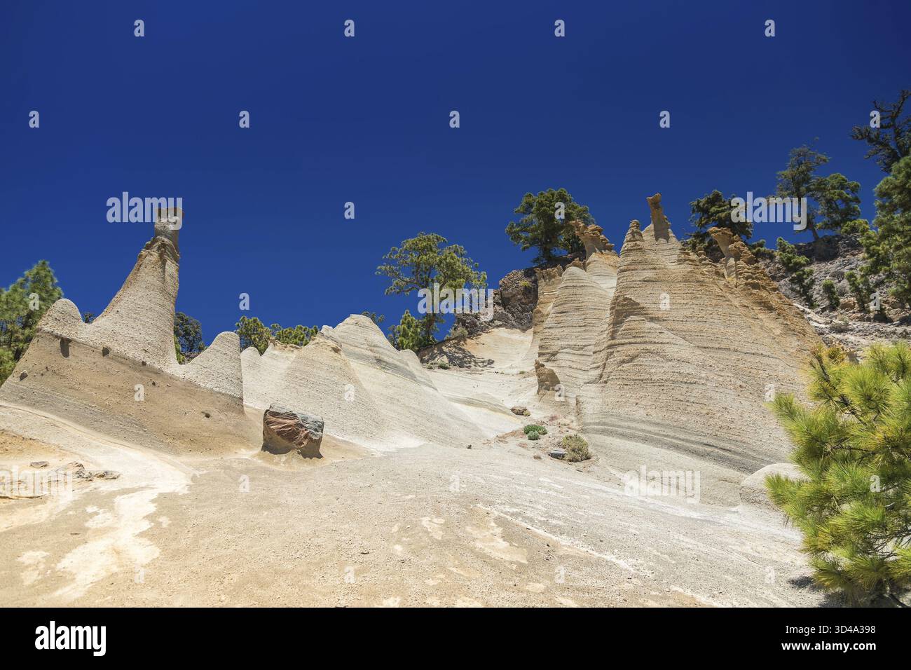 Die auffälligen Hoodoos von Paisaje Lunar auf Teneriffa sind ein herausragendes Merkmal vor einem klaren blauen Himmel und grünen Kiefern. Diese einzigartigen Felsformationen machen das Stockfoto