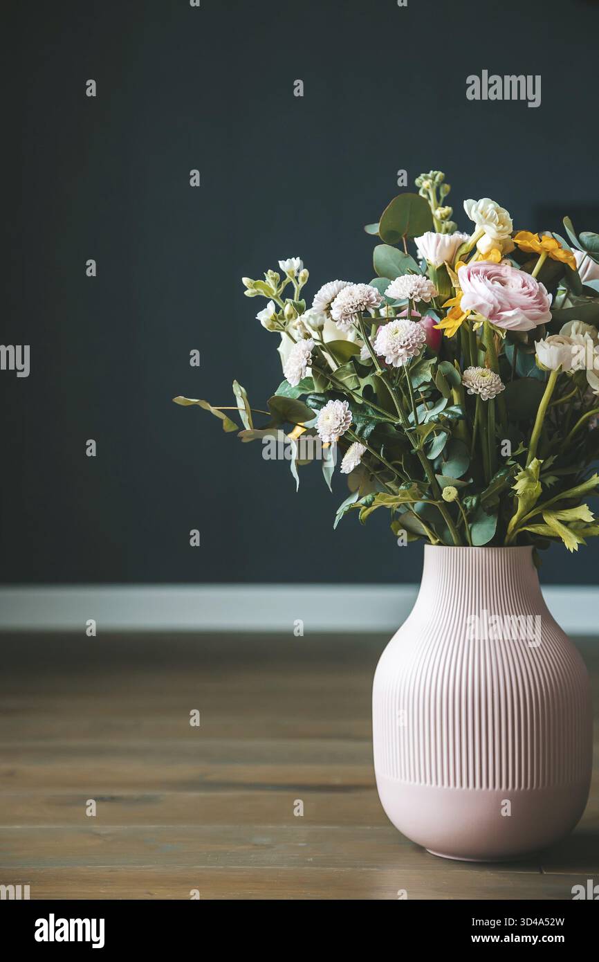 Ein stilvolles Blumenarrangement in einer rosafarbenen Vase vor dunklem Hintergrund, das eine schicke und anspruchsvolle Ästhetik für die Inneneinrichtung bietet. Konzept: Home Stockfoto