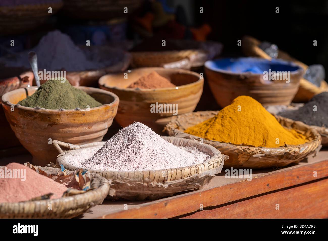 Natürliche Farbpigmente Pulver in Schüsseln auf Holztisch in Marrakesch, Marokko. Verschiedene lebhafte Farben, traditionelle Umgebung auf verschwommenem Hintergrund. Stockfoto