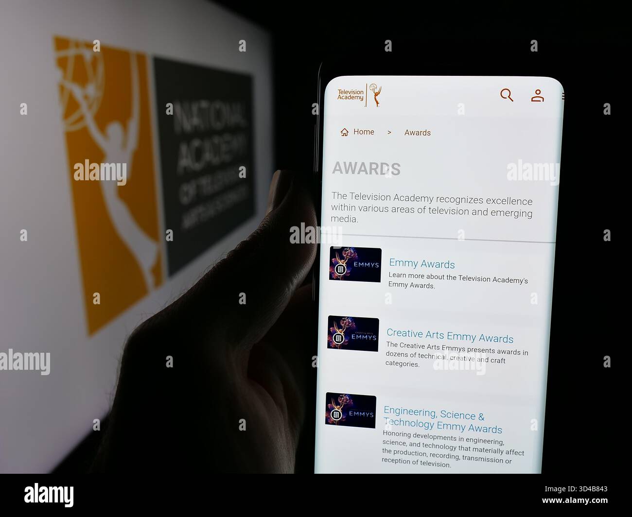 Stuttgart, Deutschland - 10-31-2025: Person, die ein Smartphone hält, mit Webseite des US-amerikanischen Fernsehpreises Emmys (Emmys) vor dem Logo auf dem Bildschirm. Stockfoto