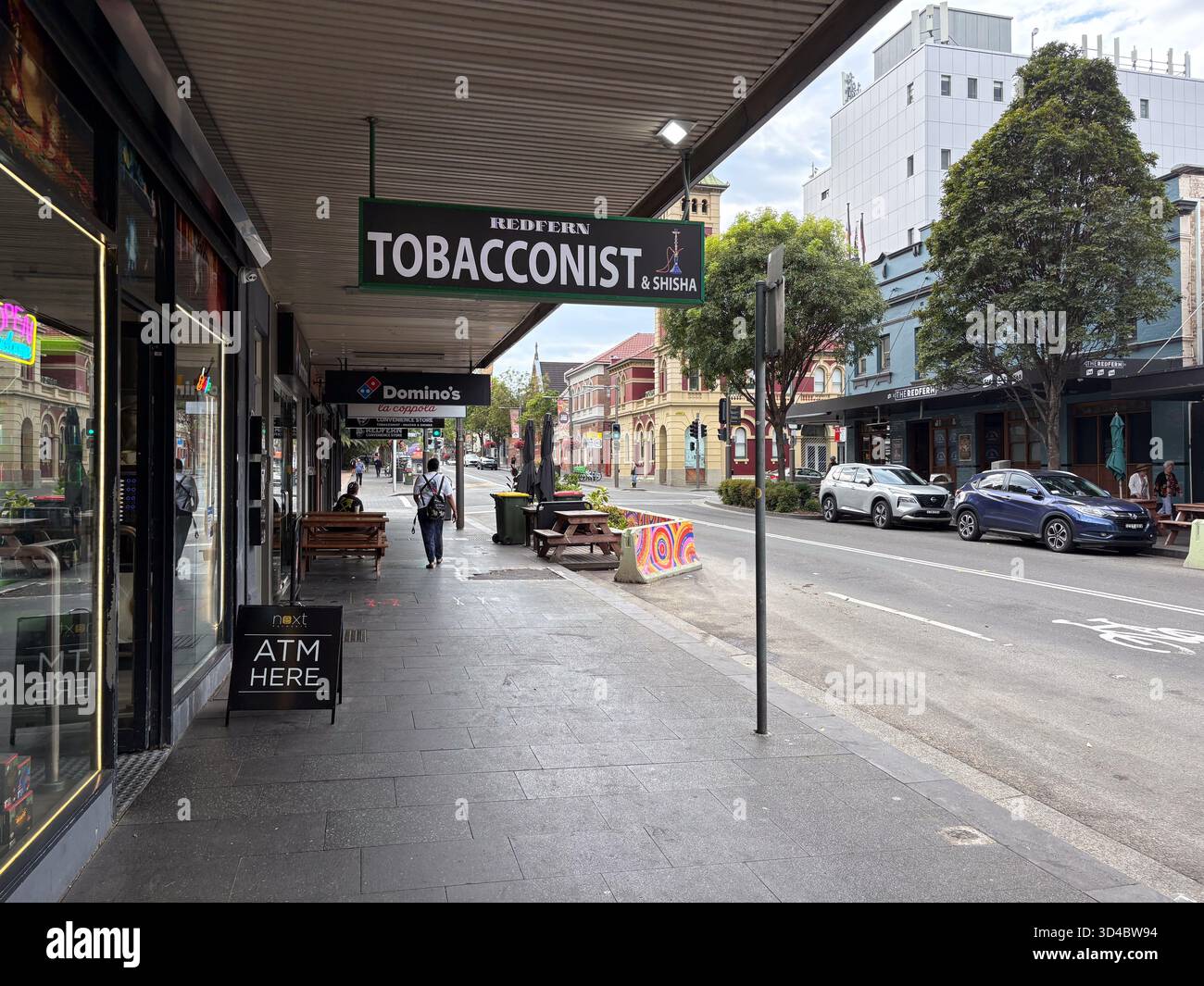 Redfern Tabak und Shisha Shopfront mit Blick auf die Straße, Menschen, die auf dem Bürgersteig laufen, und Autos, die in einem belebten Geschäftsviertel von Sydney, Au, parken Stockfoto