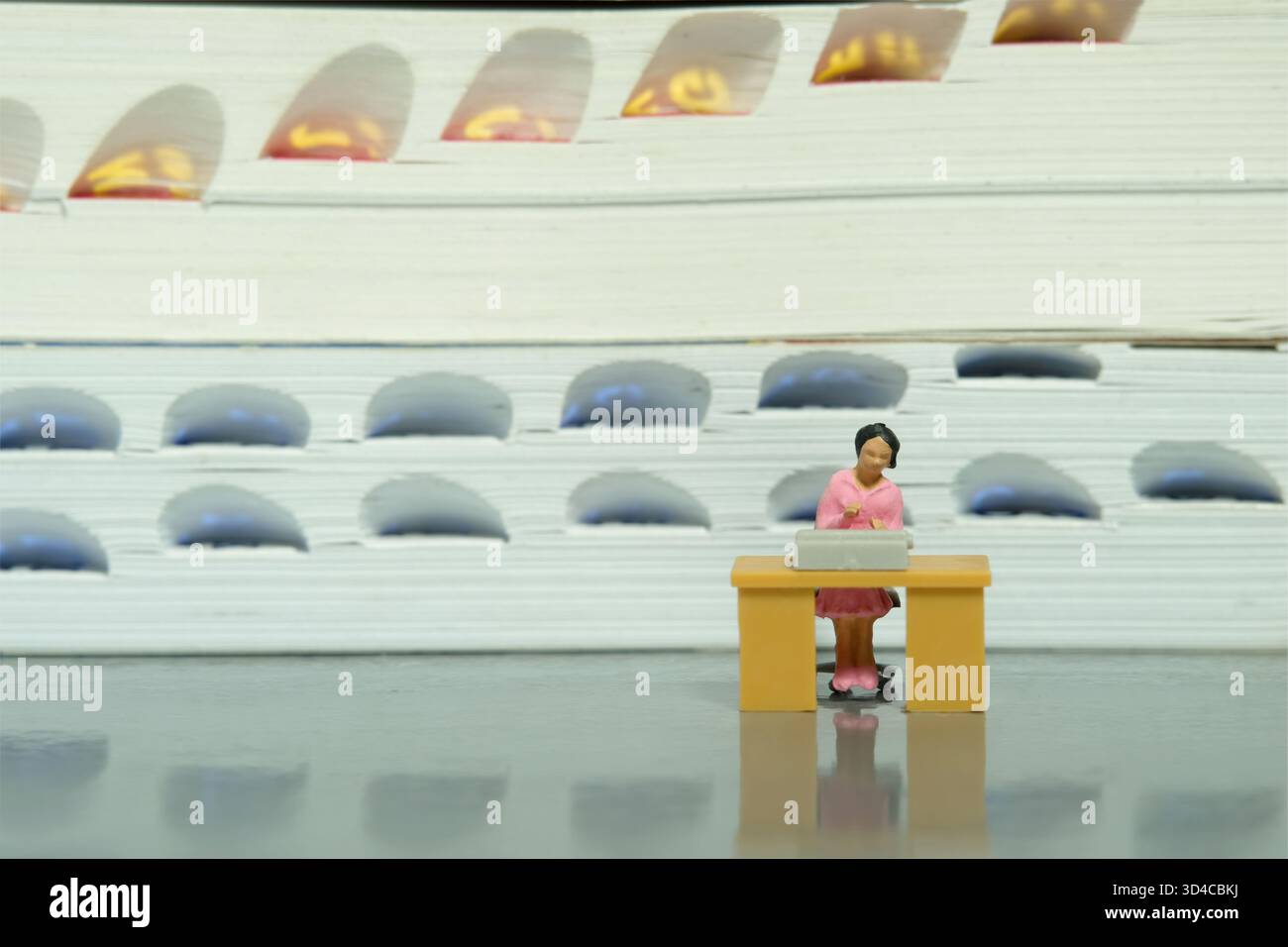 Miniatur-Kleinkinder-Spielfiguren-Fotografie. Eine weibliche Bibliothekarin sitzt auf dem Schreibtisch vor dem Bücherregal. Bild Foto Stockfoto