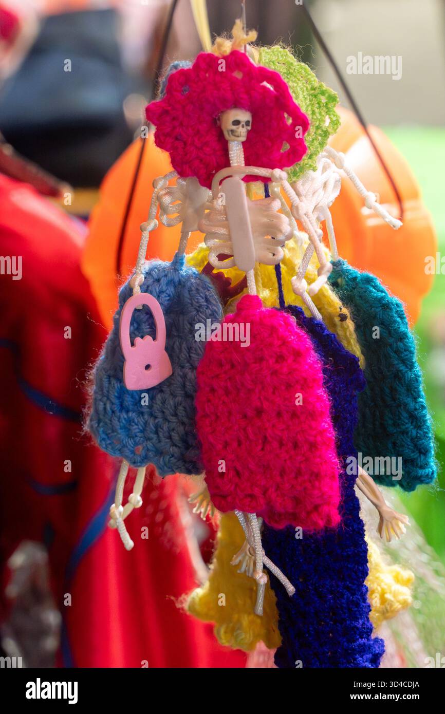 Eine bunte Auswahl an Strickgegenständen, darunter ein Skelett, hängt an einer Schnur. Mexikanischer Tag der Toten Tradition, Opfer, Essen, Farben, d Stockfoto