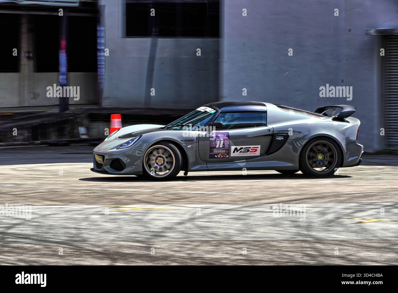 Ein schlanker, grauer Lotus Exige Sportwagen, der auf einer offenen Strecke fährt, in Bewegung gehalten wird und einen unscharfen Hintergrund für Geschwindigkeit und Leistung bietet. Stockfoto
