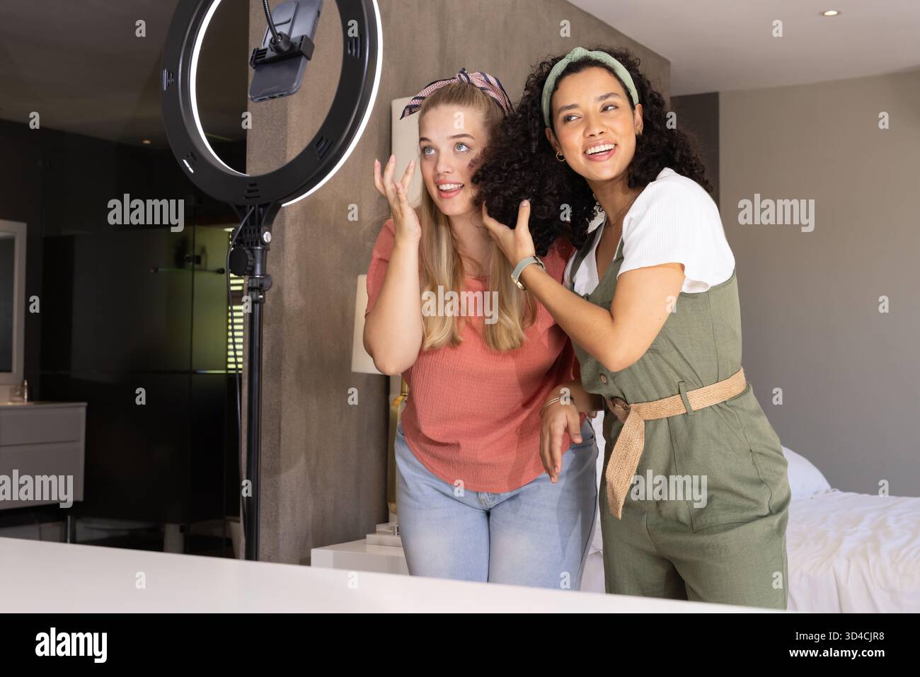 Aufnahmen verschiedener Freundinnen, die im Studio im Schlafzimmer Make-up auftragen, mit Ringlicht und Smartphone Stockfoto