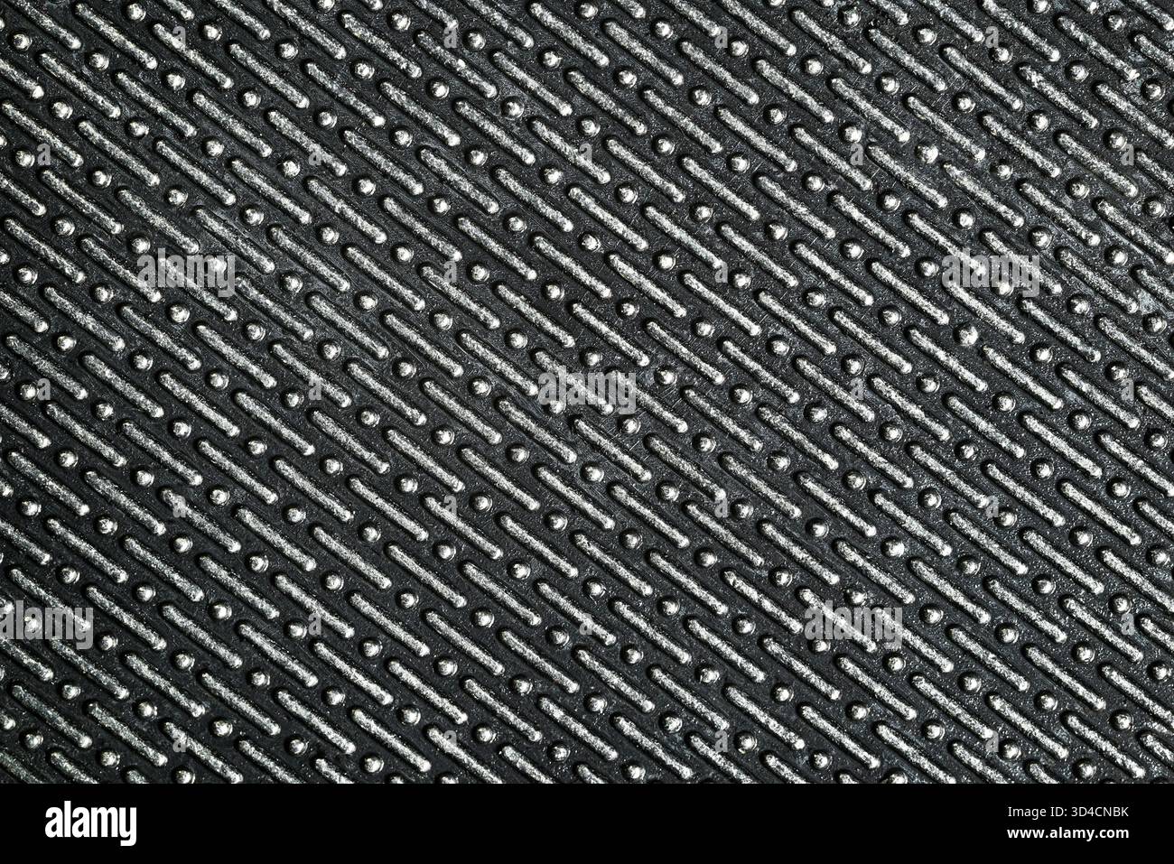Metallstruktur mit geometrischem Prägemuster. Nahaufnahme einer glänzenden metallischen Oberfläche mit sich wiederholenden Elementen. Stockfoto