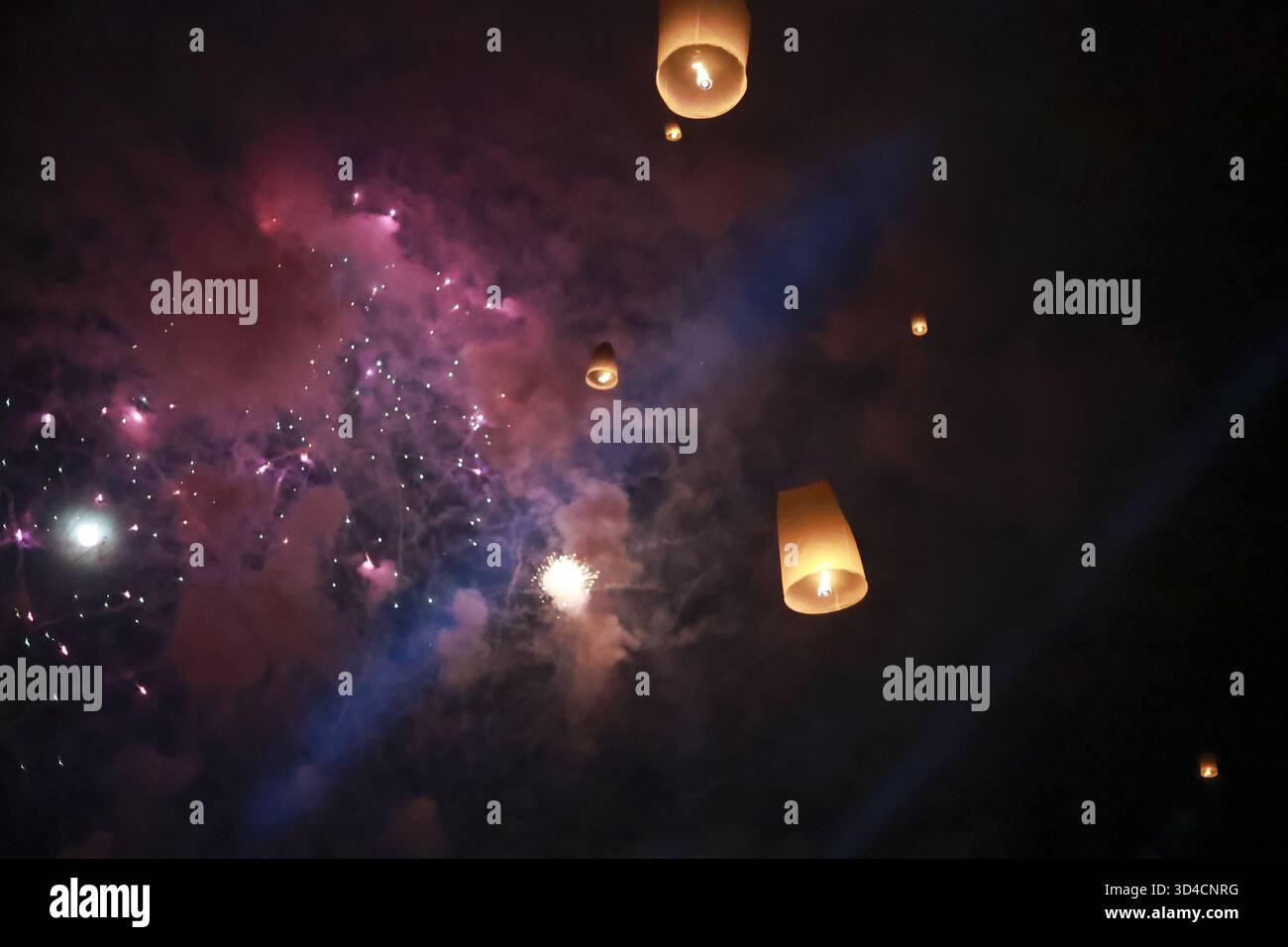 Spirituelle Festivalfeier bei Nacht mit schwimmender Himmelslaterne und farbenfrohem Feuerwerk. Wunderschönes Licht am dunklen Himmel inspiriert ein magisches und hoffnungsvolles Gefühl Stockfoto