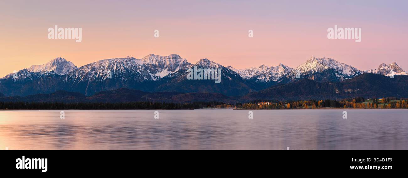 Großer Panoramablick auf den Sonnenaufgang über Hopfensee in Hopfen am See, Bayern, Deutschland, aufgenommen in einem filmischen 65:24 XPan-Format. Das stille Wasser des Sees Stockfoto