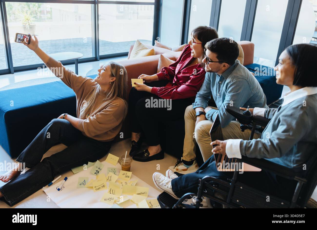 Verschiedene Gruppen von Erwachsenen arbeiten in einem Büro zusammen, um einen Moment mit einem Selfie festzuhalten. Stockfoto