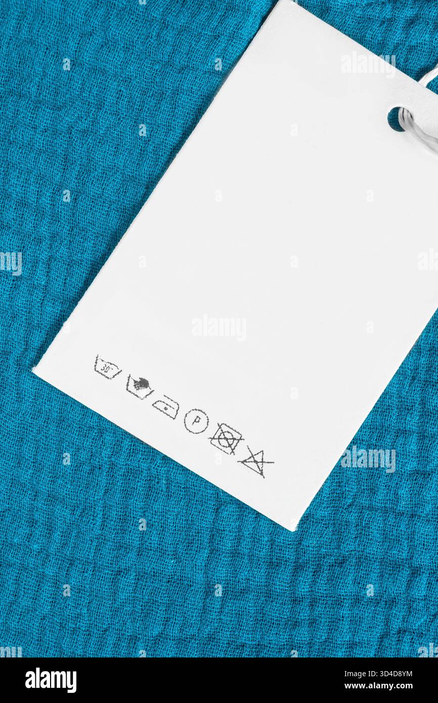 Waschanweisungen Kleideretikett über blauem Baumwollstoff Hintergrund Stockfoto