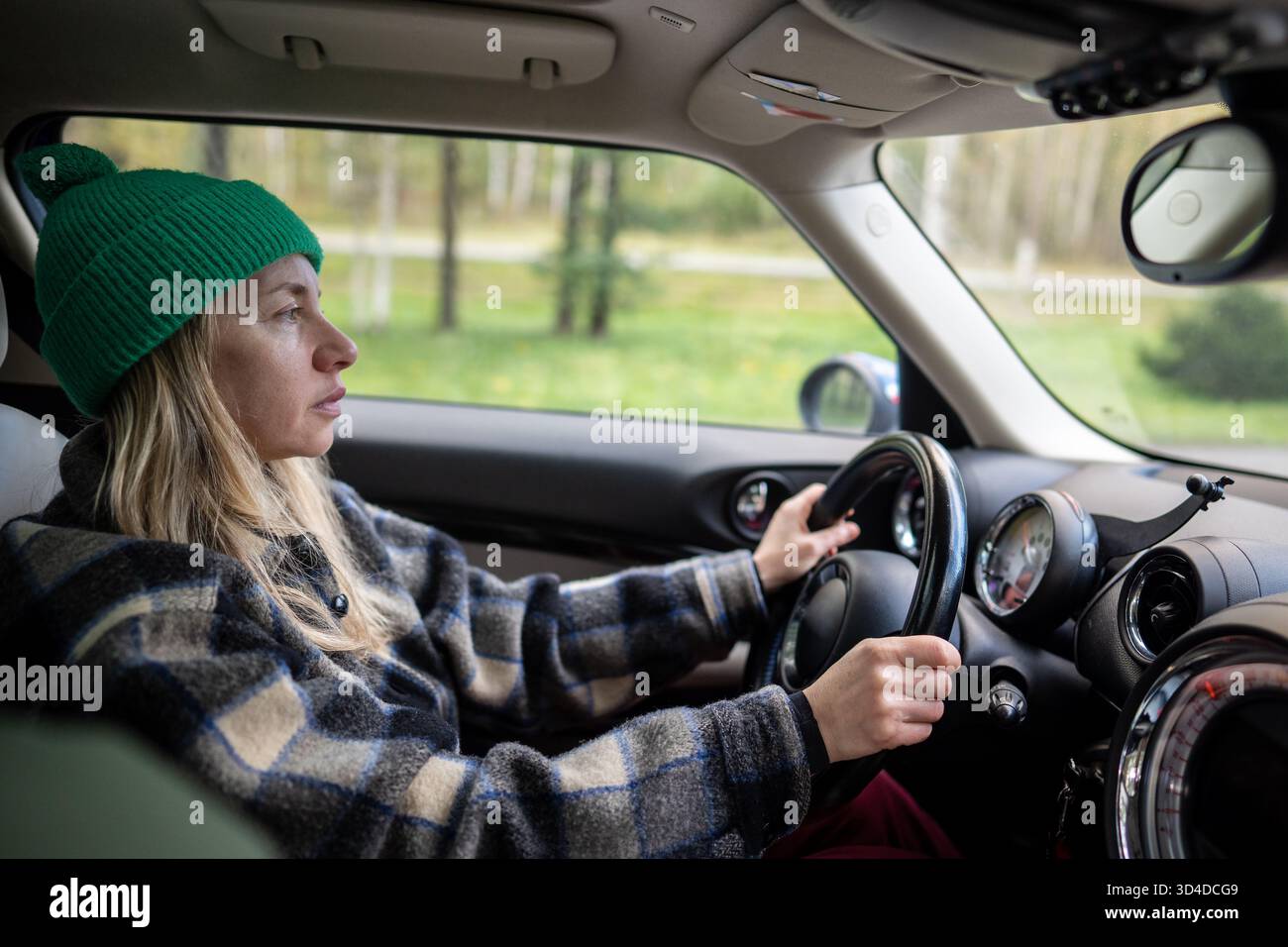 Selbstbewusste Frau, die auf offener Straße Auto fährt. Innengewinde, Einzelfahrt, Seitenansicht Stockfoto