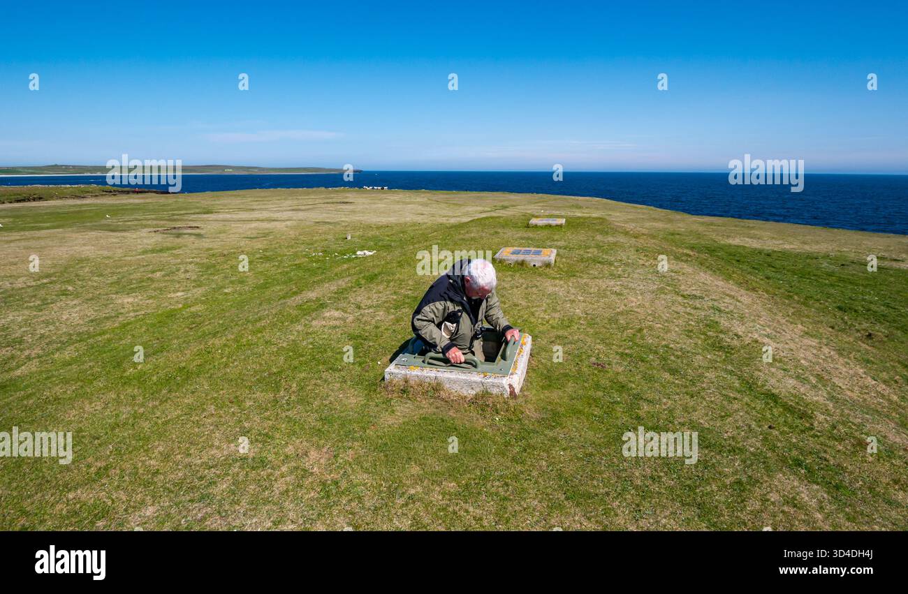 Senior man klettert aus der neolithischen Grabkammer oder aus dem kammerten Kairn, Holm of Papa, Papa Westray, Orkney-Inseln, Schottland, UK Stockfoto