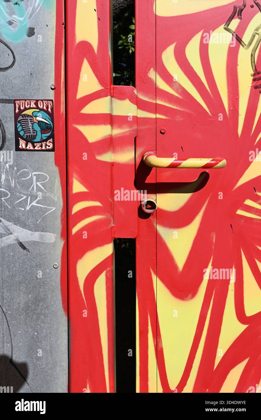 Sicherheitstür aus Metall oder Eingang in modernem abstrakten Graffiti mit farbenfrohen roten und gelben Türgriffen Stockfoto