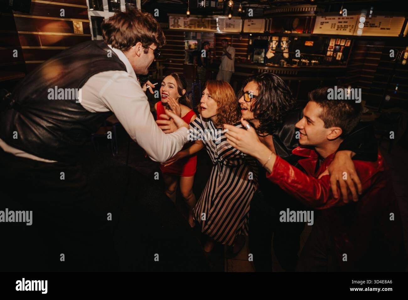 Freunde feiern einen lebhaften Abend und teilen Lachen und Musik in einer lebhaften Bar-Atmosphäre Stockfoto