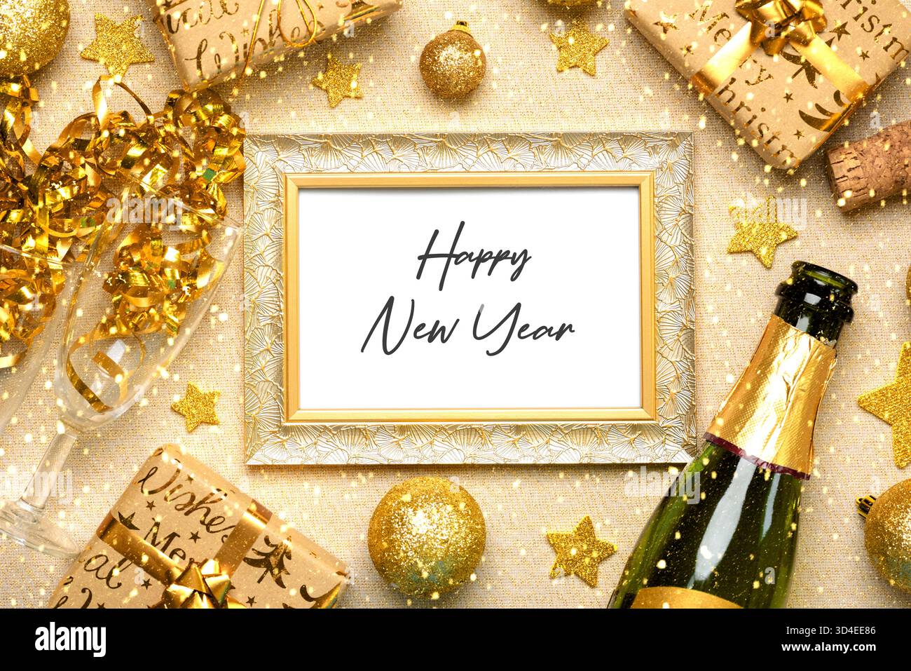Blick von oben auf den goldenen Rahmen mit dem Text Happy New Year, Flasche Champagner, Kristallgläser und goldene weihnachtskugeln auf einer goldenen Glitzertischdecke. Neu Stockfoto