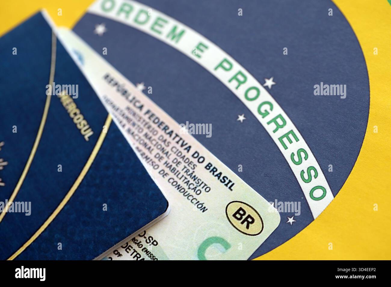 Brasilianischer Führerschein für ein Kraftfahrzeug mit Reisepass auf brasilianischer Flagge in Nahaufnahme Stockfoto