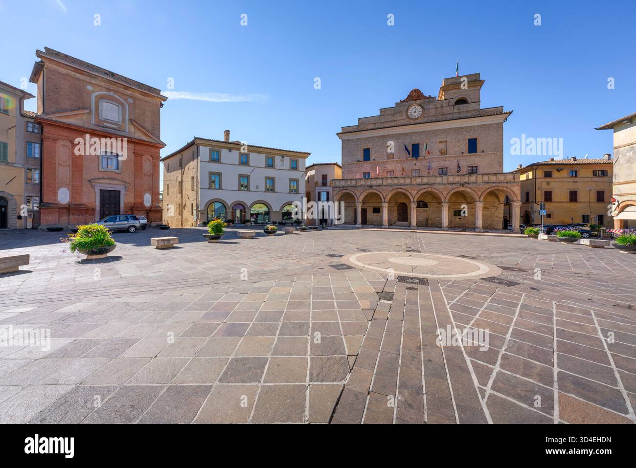 Blick auf die Piazza del Comune, den zentralen Platz der mittelalterlichen Bergstadt Montefalco, Umbrien. Mit dem historischen Palazzo Comunale unter blauem Himmel Stockfoto