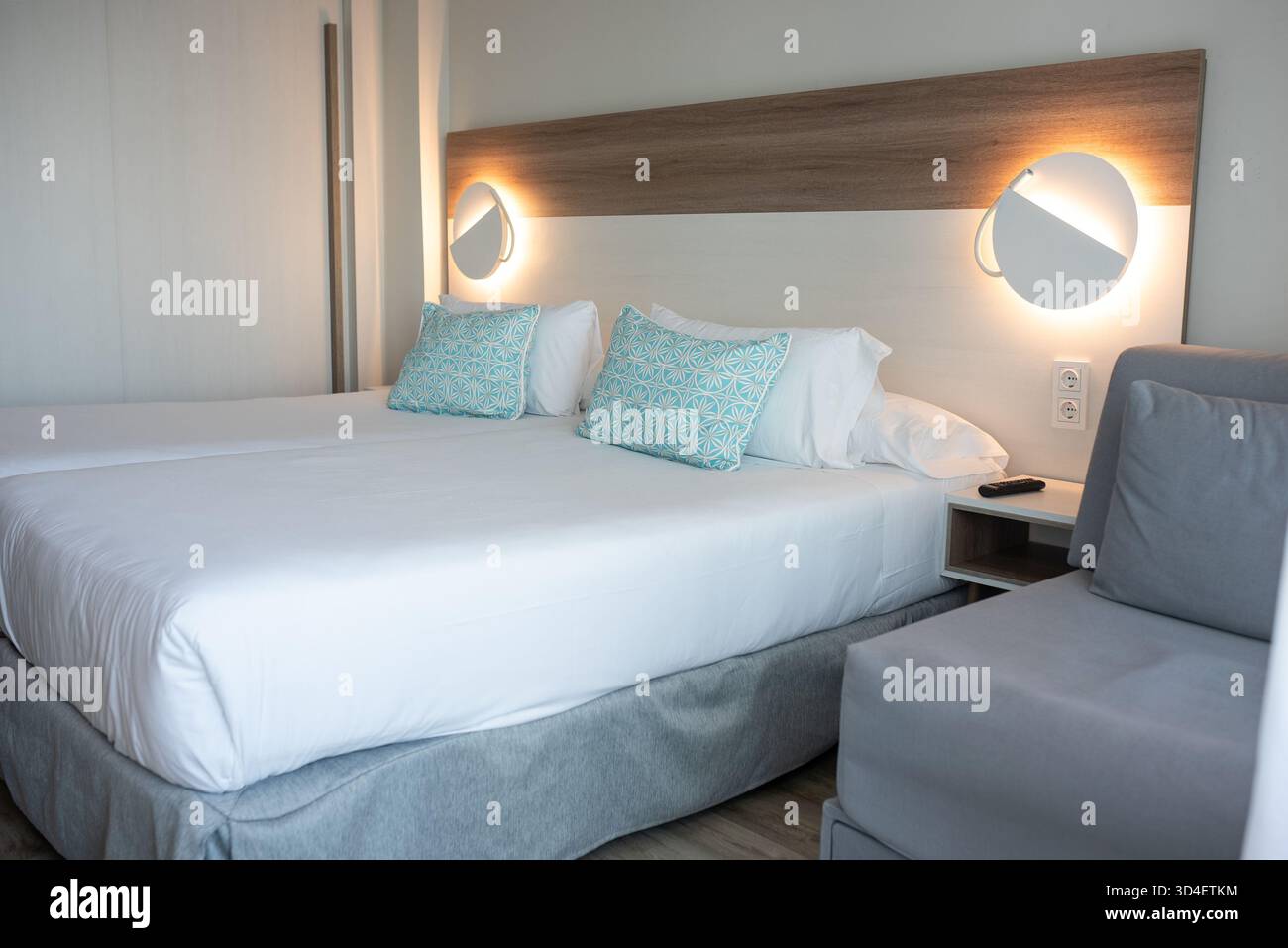 Das moderne Hotelzimmer verfügt über zwei Betten mit dekorativen Kissen und sanfter Beleuchtung Stockfoto