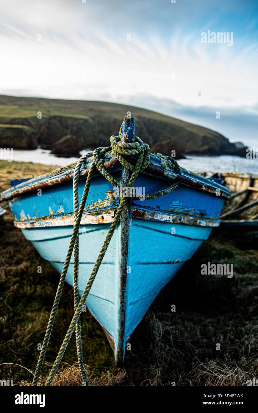 Ein heruntergekommenes Boot an der Küste mit einem Seil, das von vorne kommt Stockfoto