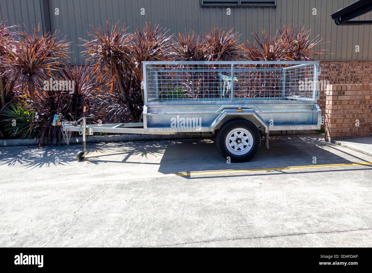 Foto eines geparkten, verzinkten Stahlanhängers mit einer achse und einem Gitterkäfig zur sicheren Aufbewahrung verschiedener Arten von Gegenständen. Stockfoto