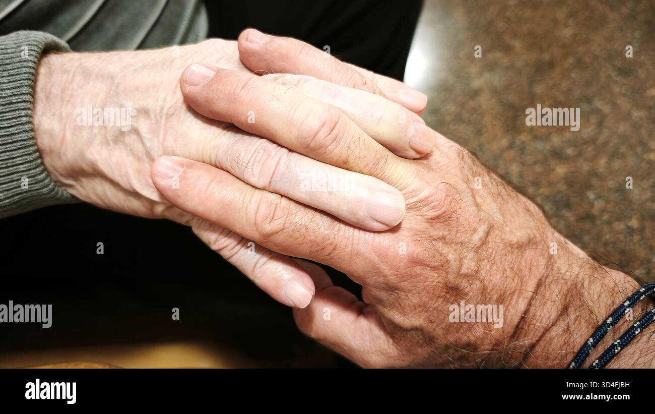 Ein Mann und ein älterer Mann halten die Hände. Konzept der Hilfe, Zusammenarbeit. Die Szene ist warm, tröstend und spiegelt Liebe und Verständnis wider. Stockfoto