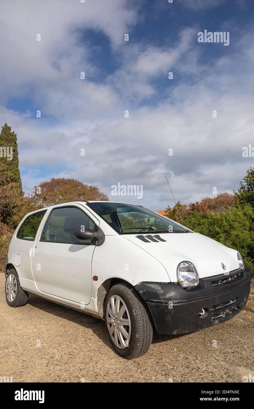 GROHOTE, KROATIEN, 10.23.2025: Ein kleiner weißer Renault Fließheck, der auf einer Schotterstraße geparkt ist und von Herbstbäumen umgeben ist. Helles Sonnenlicht und eine ruhige, ländliche Umgebung Stockfoto