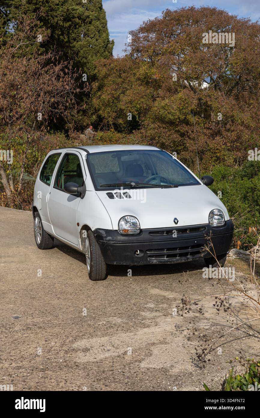 GROHOTE, KROATIEN, 10.23.2025: Ein kleiner weißer Renault Fließheck, der auf einer Schotterstraße geparkt ist und von Herbstbäumen umgeben ist. Helles Sonnenlicht und eine ruhige, ländliche Umgebung Stockfoto